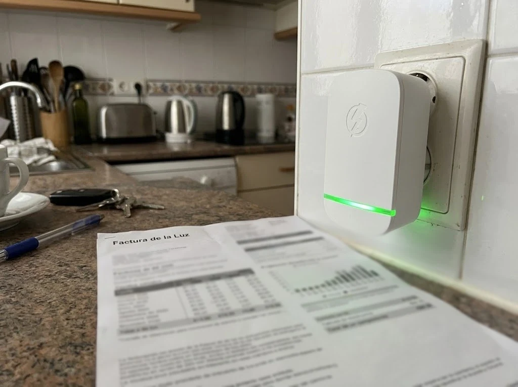 StopWatt enchufado en la cocina junto a una factura de la luz